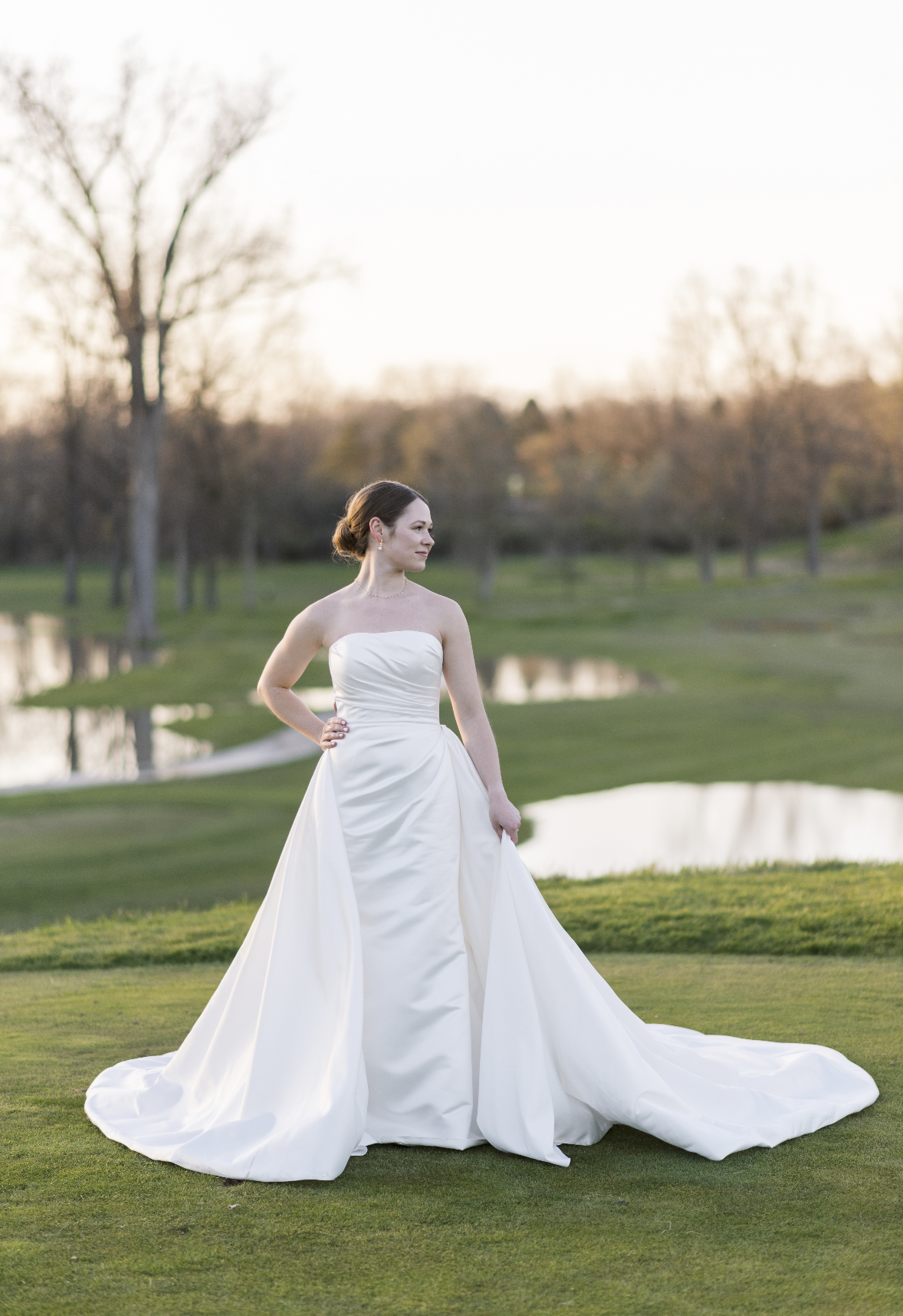 Bride looking to the right on a golf course after the wedding ceremony. Her dress is large and beautiful on the spring grass.